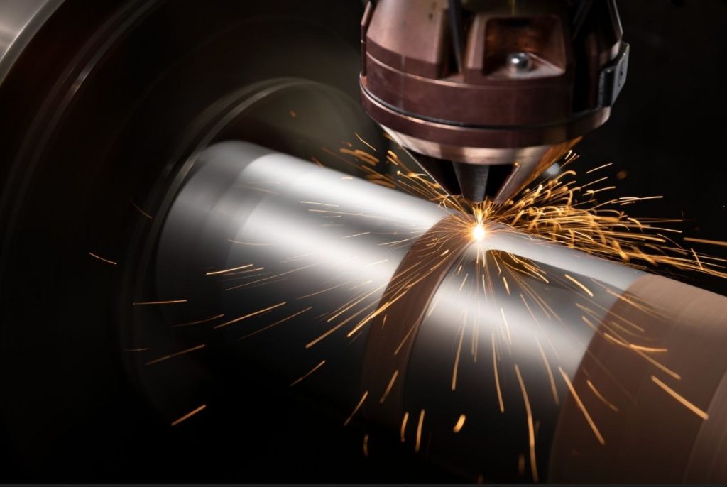 CNC-Laser schneidet oder schweisst rotierenden Zylinder mit goldenen Funken